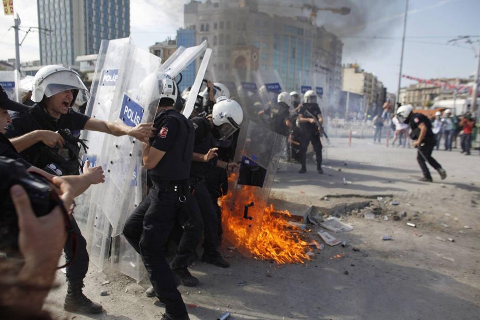 A petrol bomb explodes in front of riot policemen during clashes in Taksim square in Istanbul, Tuesday, June 11,2013. Hundreds of police in riot gear forced through barricades in Istanbul's central Taksim Square early Tuesday, pushing many of the protesters who had occupied the square for more than a week into a nearby park. (AP Photo/Kostas Tsironis)