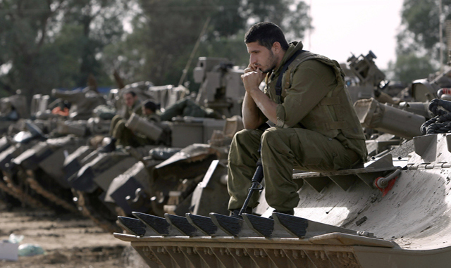 Israeli soldiers with armored vehicles gather in a staging ground near the border with Gaza Strip, southern Israel, Friday, Nov. 16, 2012. Fierce clashes between Israeli forces and Gaza militants are continuing for the third day.(AP Photo/Tsafrir Abayov)