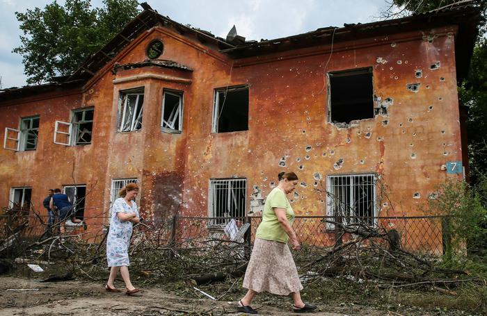 epa04359333 Residents walk past a damaged house after Ukranian army shelling downtown of Khartsyzk (24km from Donetsk), Ukraine, 18 August 2014. Russian Foreign Minister Sergei Lavrov said 18 August that a political settlement of the conflict in Ukraine was possible only if the government in Kiev halted its military campaign against separatist rebels in the east.  EPA/SERGEI ILNITSKY