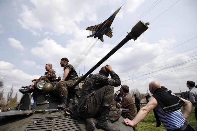 A fighter jet flies above as Ukrainian soldiers sit on an armoured personnel carrier in Kramatorsk, in eastern Ukraine April 16, 2014. Ukrainian government forces and separatist pro-Russian militia staged rival shows of force in eastern Ukraine on Wednesday amid escalating rhetoric on the eve of crucial four-power talks in Geneva on the former Soviet country's future.  REUTERS/Marko Djurica (UKRAINE - Tags: POLITICS CIVIL UNREST MILITARY TPX IMAGES OF THE DAY)