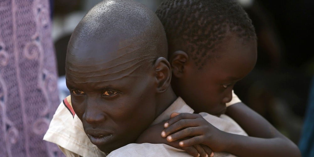 An internally displaced man holds his son inside a United Nations Missions in Sudan (UNMIS) compound in Juba December 19, 2013. South Sudanese government troops battled to regain control of a flashpoint town and sent forces to quell fighting in a vital oil producing area on Thursday, the fifth day of a conflict that that has deepended ethnic divisions in the two-year-old nation. REUTERS/Goran Tomasevic (SOUTH SUDAN - Tags: POLITICS CIVIL UNREST)
