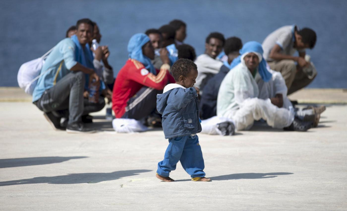 A children walks as migrants rest after disembarking from the expedition vessel Phoenix in the Sicilian harbour of Augusta, Italy June 17, 2015. REUTERS/Antonio Parrinello