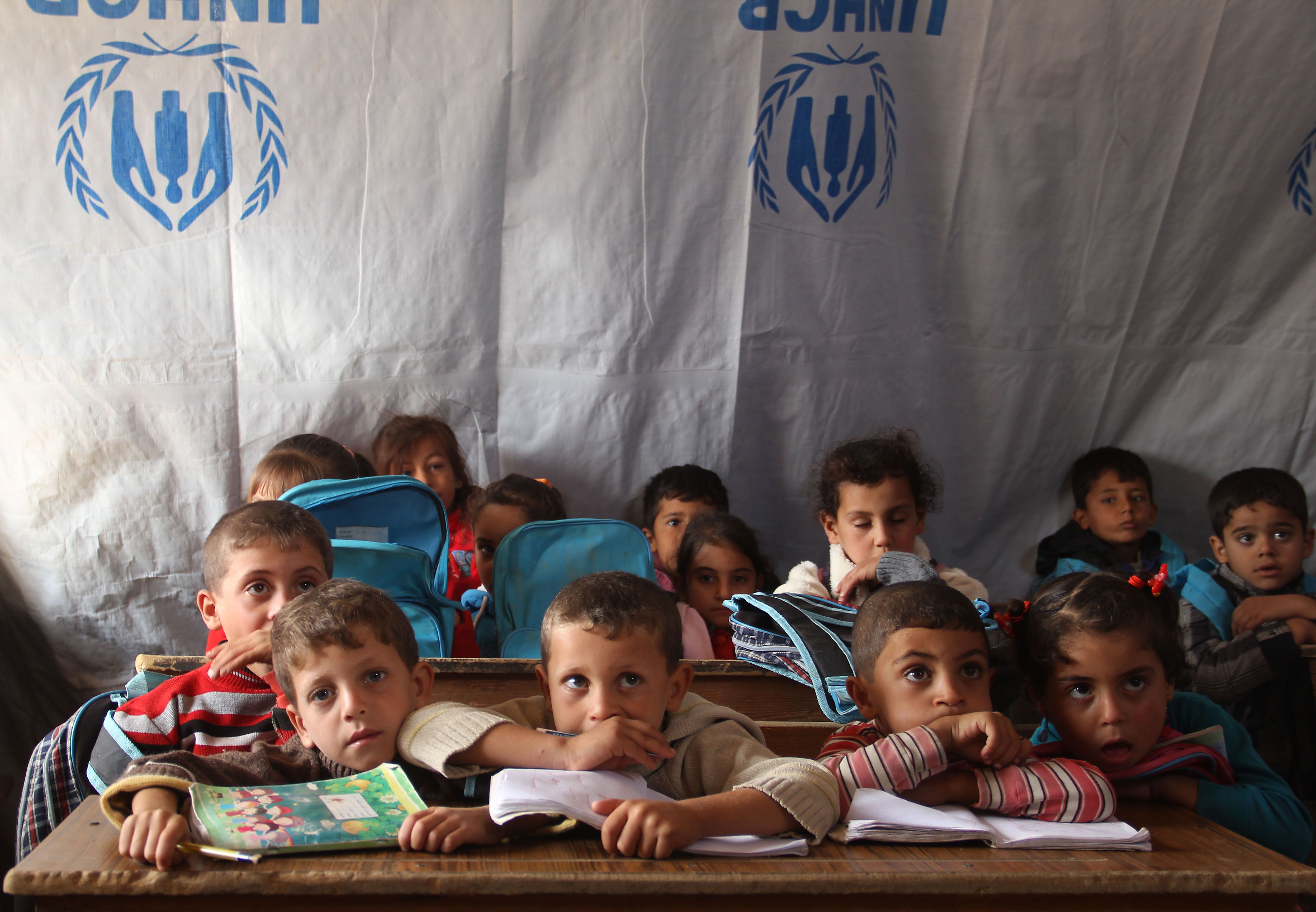 Displaced Syrian children from the town of Daraa, sit at a makeshift school set up in a tent provided the United Nations agency for refugees UNHCR, in the Daraa area in southern Syria, on October 27, 2015. Syrian government forces and rebels fighters have been battling for the control the Daraa area . AFP PHOTO / MOHAMAD ABD ABAZID