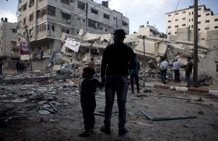 Palestinians stand in front of a destroyed multi-story building was hit by Israeli airstrikes late Saturday in Gaza City, Sunday, May 5, 2019. Palestinian militants on Saturday fired over 200 rockets into Israel, drawing dozens of retaliatory airstrikes on targets across the Gaza Strip in a round of intense fighting that broke a monthlong lull between the bitter enemies. (ANSA/AP Photo/Khalil Hamra) [CopyrightNotice: Copyright 2019 The Associated Press. All rights reserved.]
