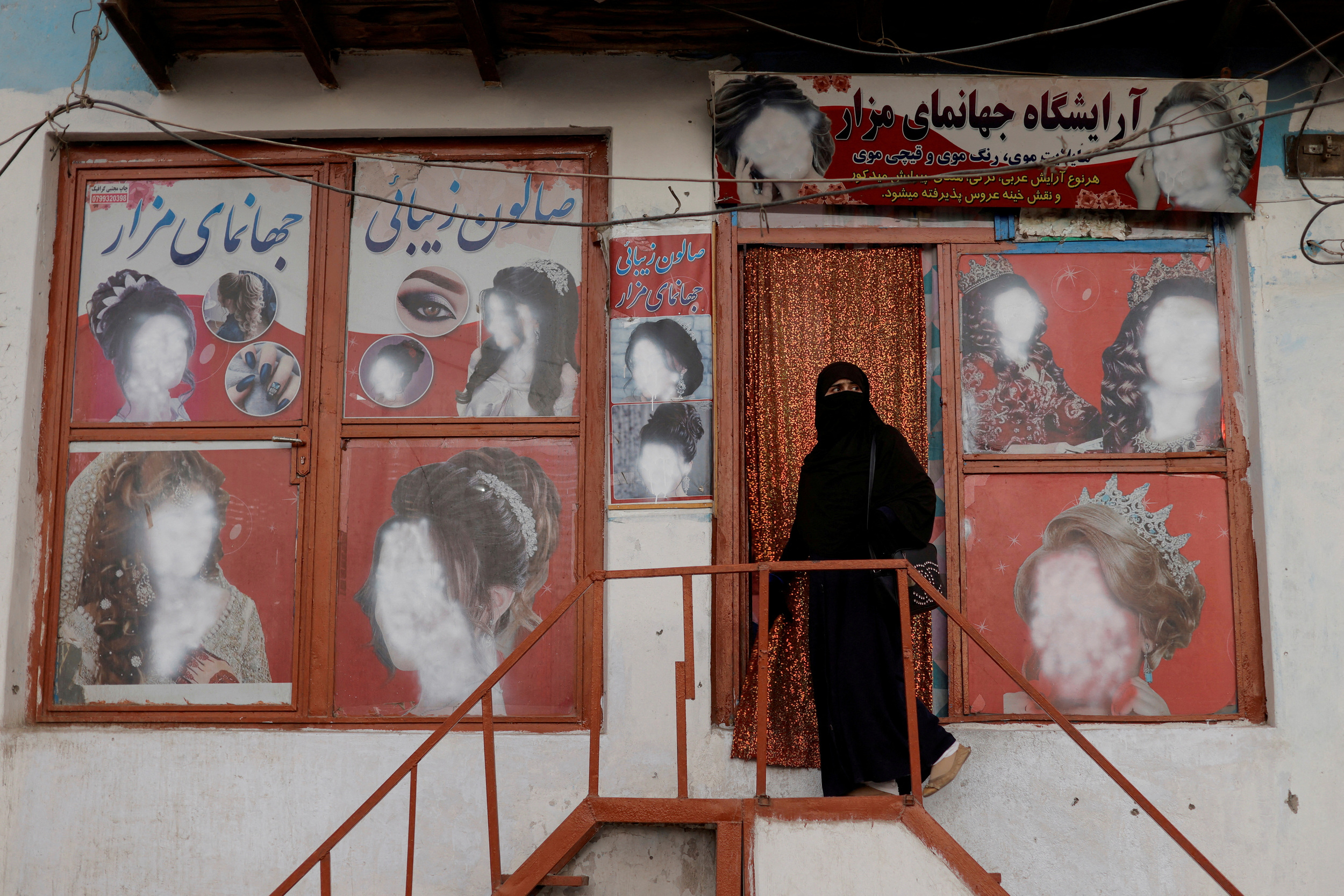 FILE PHOTO: A woman wearing a niqab enters a beauty salon where the ads of women have been defaced by a shopkeeper in Kabul, Afghanistan October 6, 2021. REUTERS/Jorge Silva/File Photo