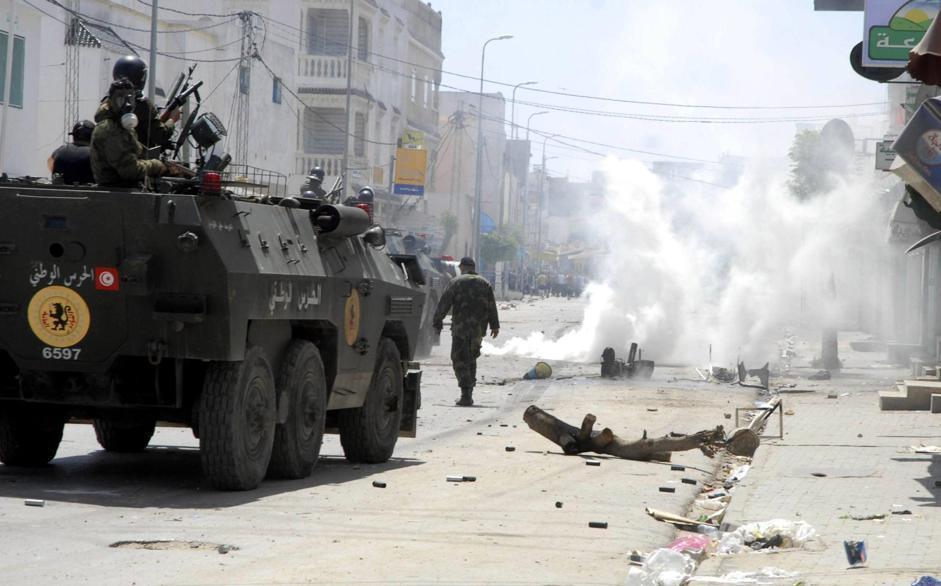 epa03707647 Tunisian riot police forces fire tear gas during clashes with supporters of Islamist group Ansar al-Sharia at Hai al Tadamon in Tunis, Tunisia, 19 May 2013. Security forces and hardline Islamists clashed in Tunisia after authorities banned the Ansar al-Sharia group from holding its annual congress. Supporters of the Salafist movement blocked streets in the capital Tunis with burning barricades and threw stones. Police fired tear gas and rubber bullets to disperse them.  EPA/STR
